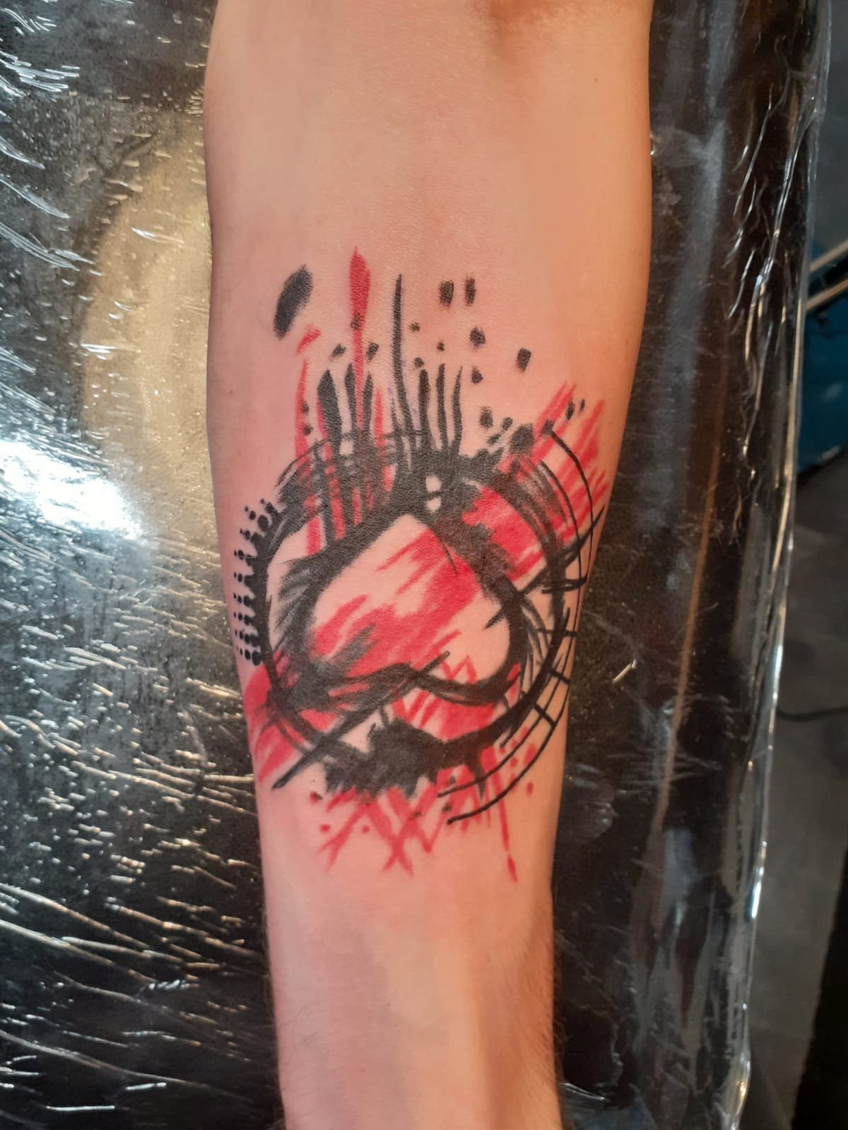 Abstract red and black brushwork forearm tattoo