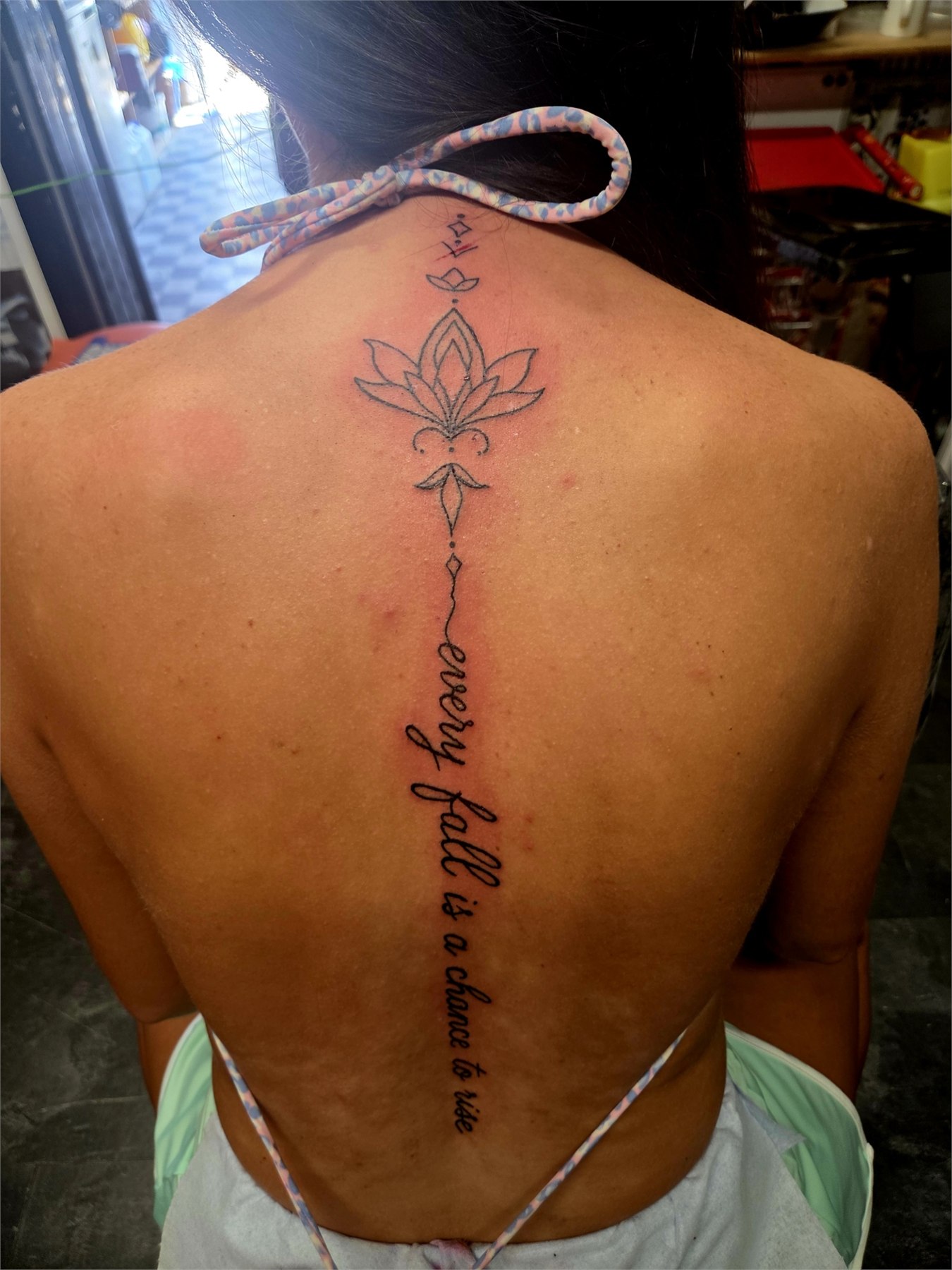 Lotus flower and vertical script spine tattoo
